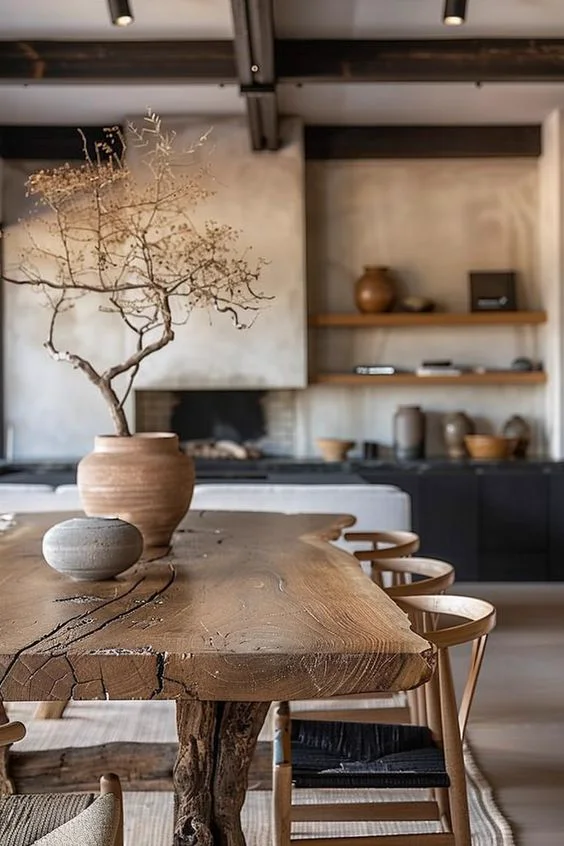Comedor con mesa de madera natural, cerámica artesanal y cocina al fondo